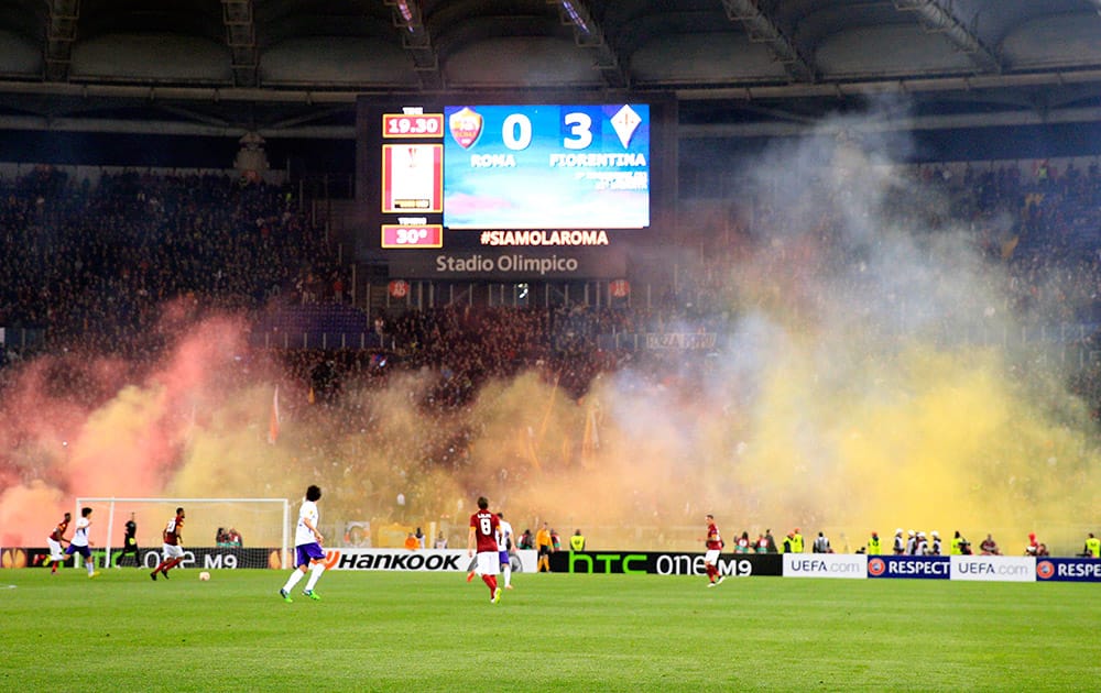 Roma supporters burn flares during an Europa League, round of 16, second leg, soccer match between Roma and Fiorentina, at Rome's Olympic Stadium.