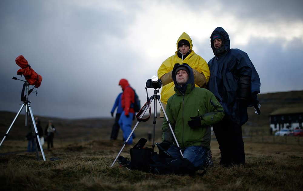 Italian visitors wait for the start of a total solar eclipse on a hill beside a hotel overlooking the sea and Torshavn, the capital city of the Faeroe Islands.