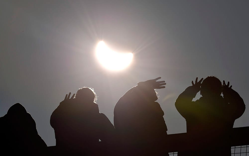 People watch as a solar eclipse begins over the Eden Project near St Austell in Cornwall, England.