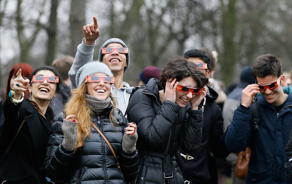 Visitors try on their solar glasses in preparation to view the solar eclipse in Regent's Park in London.