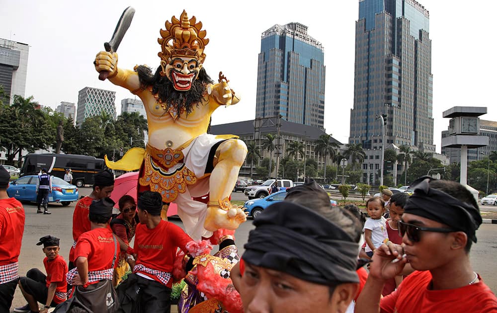 Hindu men take a break near a giant effigy called 