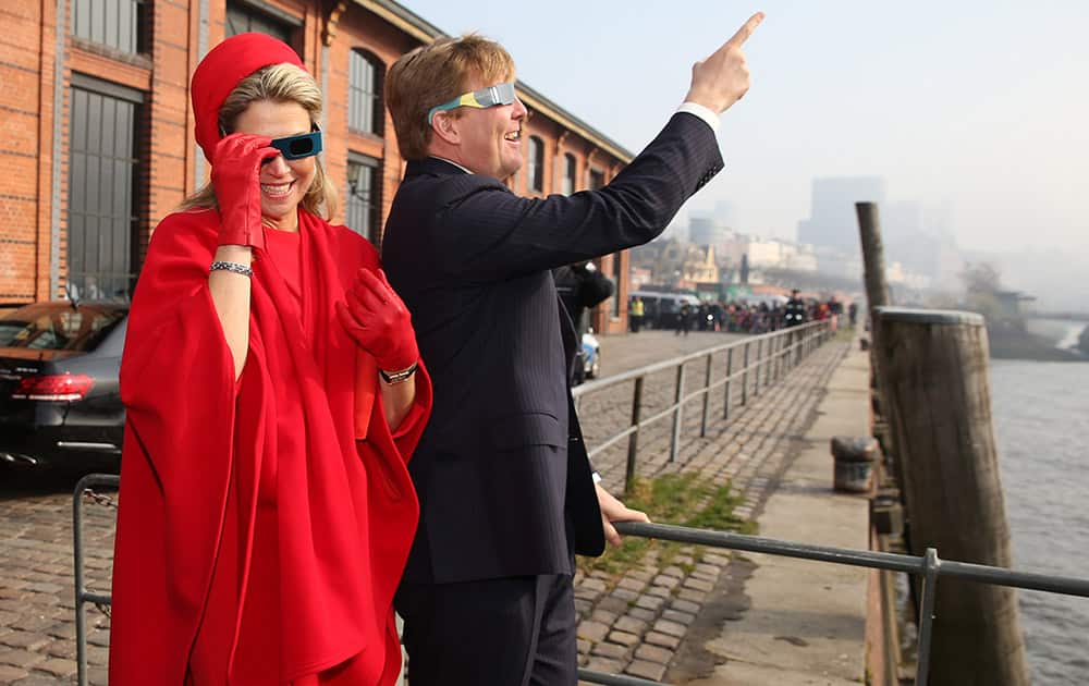 Queen Maxima and King Willem-Alexander of the Netherlands watch the solar eclipse through special glasses at the Fish Market in Hamburg, Germany.