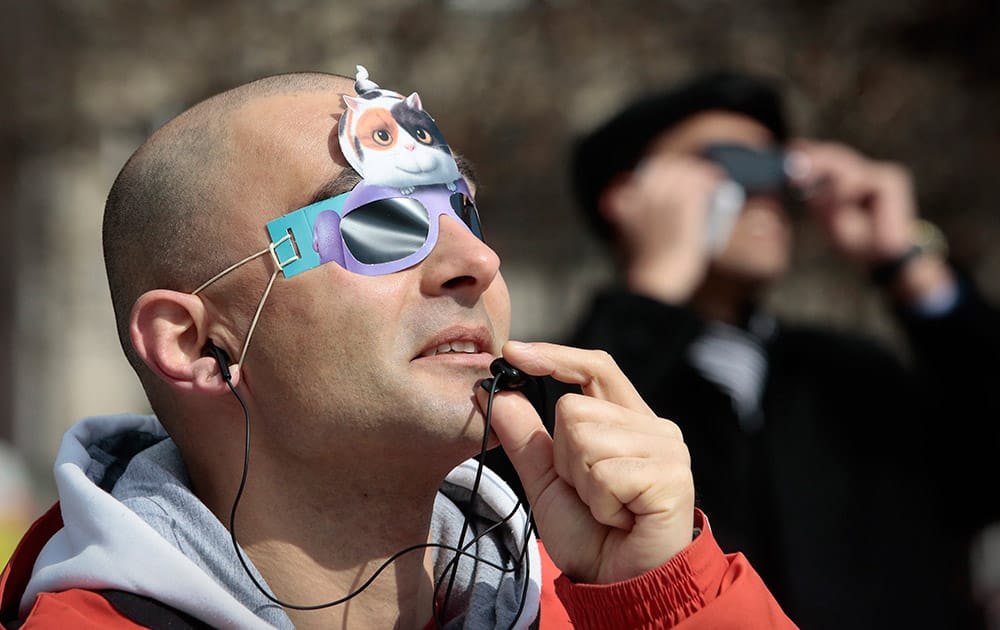 A man looks at the solar eclipse wearing protective glasses in Sofia.