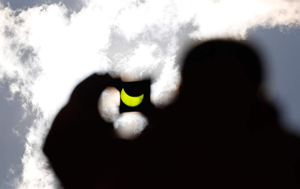 A solar eclipse is seen through a dark glass plate in Sarajevo, Bosnia.