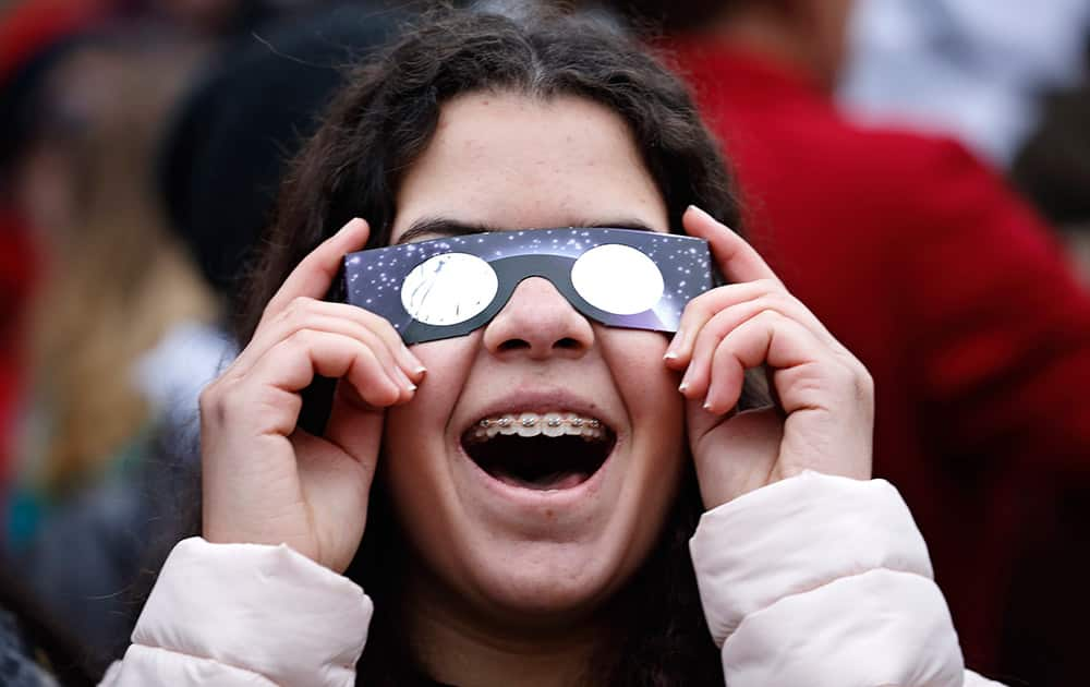 A young girl follows the solar eclipse, viewed through special glasses from the planetarium in Copenhagen.