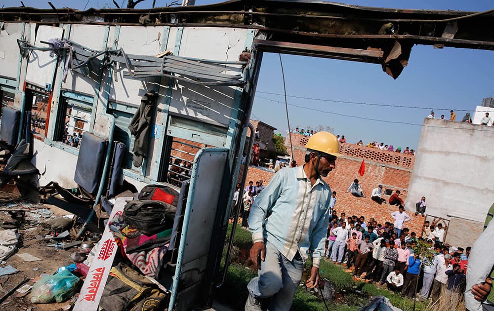 A rescue worker enters a mangled compartment of a train at the site of a train accident near Bachhrawan village, Uttar Pradesh.