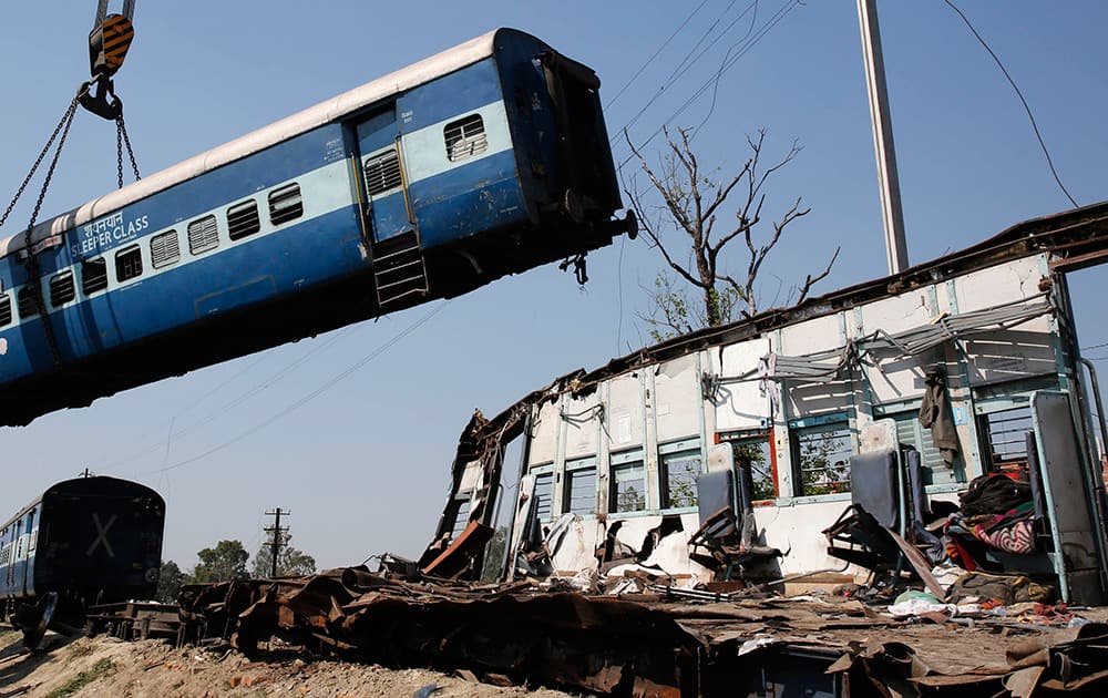 A train compartment is lifted by a crane as the mangled remains of another compartment stands at the site of an accident near Bachhrawan village in Uttar Pradesh.