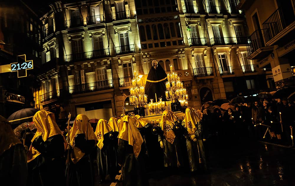 Masked penitents and devotees take part in a street in the old city during the procession of the 'La Dolorosa' brotherhood, in Pamplona northern Spain.