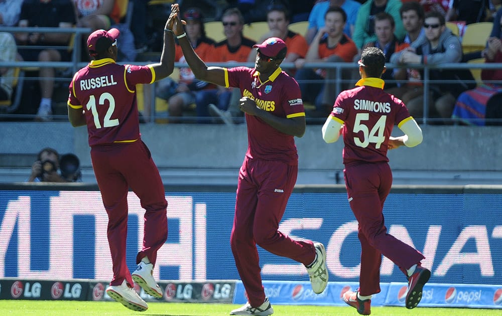 West Indies Jason Holder is congratulated by teammates Andre Russell, left, and Lendl Simmons, right, after taking a catch to dismiss New Zealand’s Brendon McCullum during their Cricket World Cup quarterfinal match in Wellington, New Zealand.