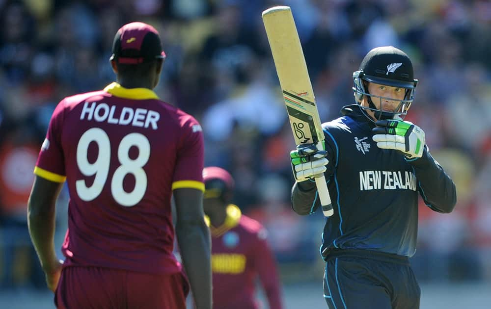 New Zealand’s Martin Guptill waves his bat as he celebrates scoring 50 runs as West Indies Jason Holder watches during their Cricket World Cup quarterfinal match in Wellington.