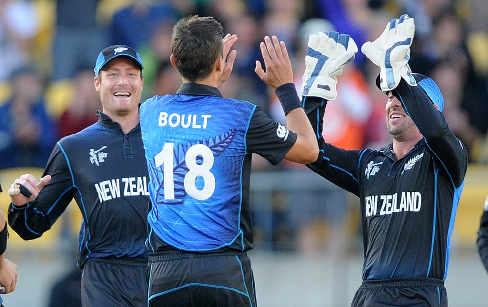 New Zealand’s Trent Boult is congratulated by teammates Martin Guptill and Luke Ronchi, right, after bowling West Indies batsman Johnson Charles during their Cricket World Cup quarterfinal match in Wellington, New Zealand.