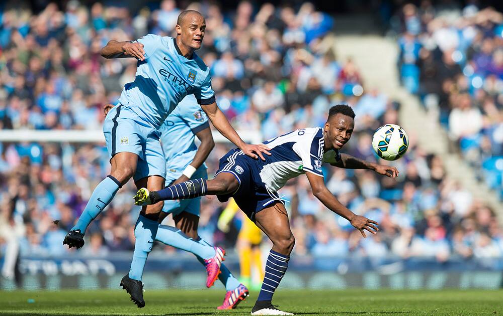 Manchester City's Vincent Kompany fights for the ball against West Bromwich Albion's Saido Berahino during the English Premier League soccer match between Manchester City and West Bromwich Albion at the Etihad Stadium, Manchester, England.