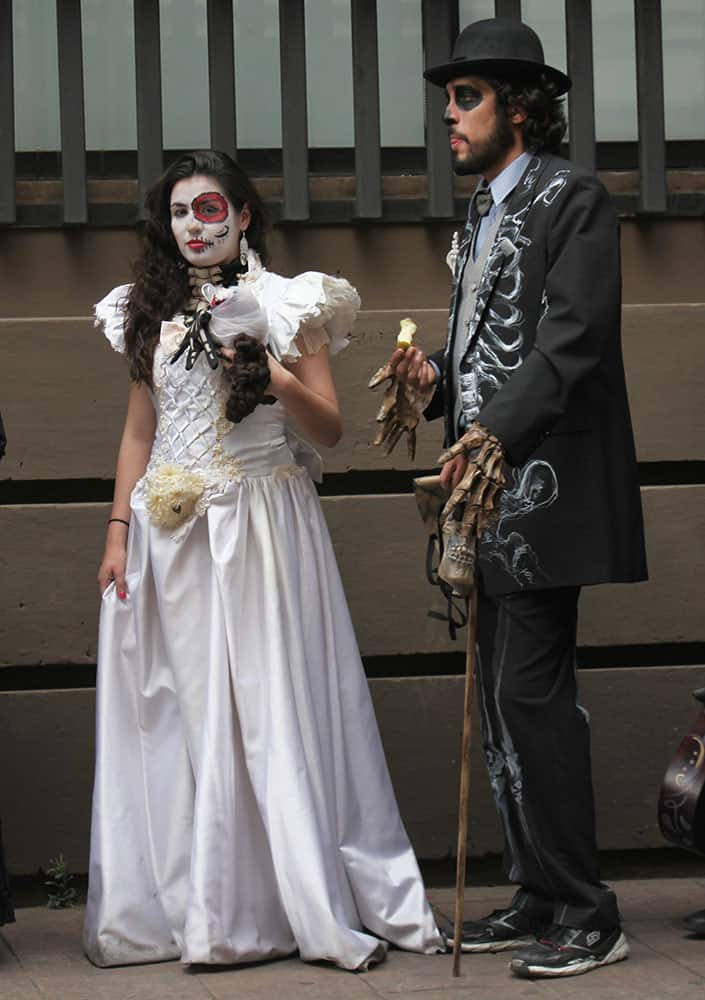 Movie extras dressed in costumes of the Day of the Dead wait for the bus after a day's filming of 