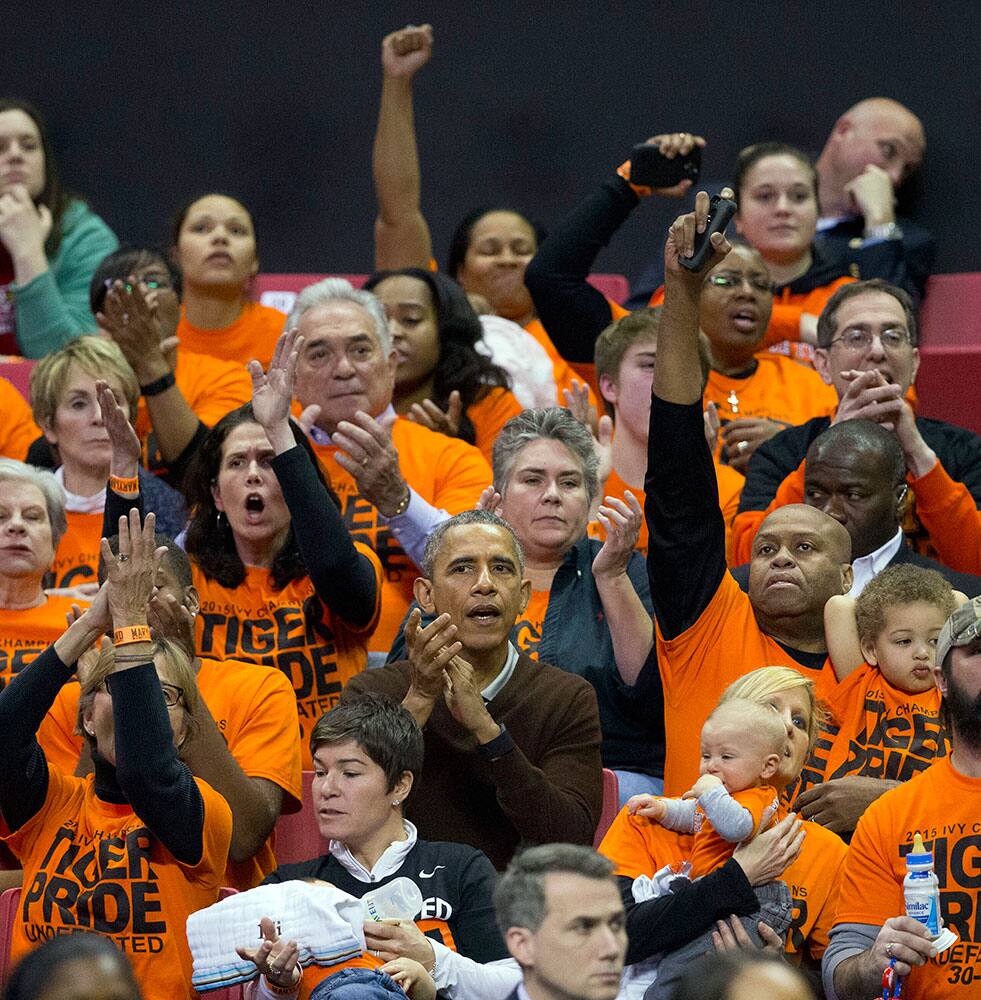 President Barack Obama, center, and his brother-in-law Craig Robinson, right, react as Princeton scores against Wisconsin-Green Bay during a women's college basketball game in the first round of the NCAA tournament in College Park, Md.