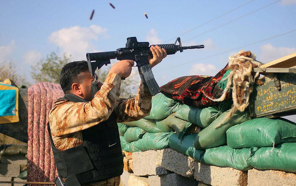 a volunteer fighter with a Shiite militant group known as 'Jihad Brigades,' fires his weapon during clashes with Islamic State group militants, outside Tikrit, 130 kilometers (80 miles) north of Baghdad, Iraq. 