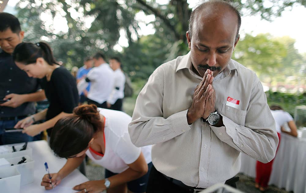 Gunasegaran S., 51, from Singapore prays quietly while other members of the public write condolence messages outside the Istana, or presidential palace, Monday, March 23, 2015, in Singapore. 