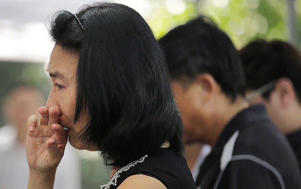 A woman holds back her tears while she reads messages of condolences left on boards erected outside the Istana, or Presidential Palace, Monday, March 23, 2015, in Singapore. 