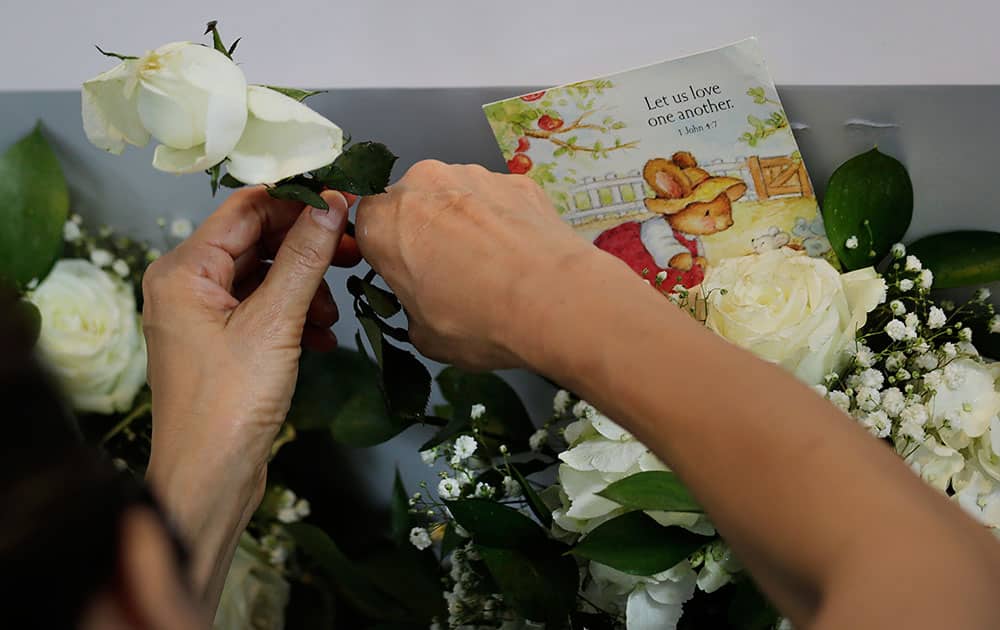 A woman adjusts a stalk of roses placed among condolence boards outside the Istana, or Presidential Palace, Monday, March 23, 2015, in Singapore. 