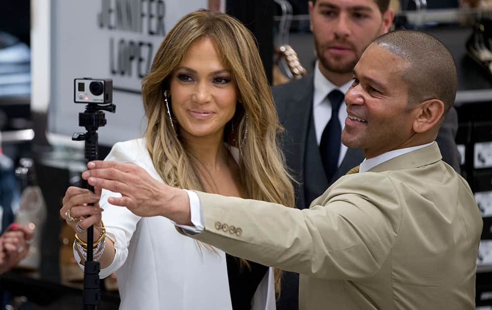 Jennifer Lopez, left, records a video during an event launching her clothing and accessories collection at a store in Mexico City.