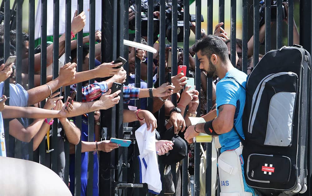Virat Kohli signs autographs for fans at a gate of the Sydney Cricket Ground during training for the Cricket World Cup in Sydney, Australia.