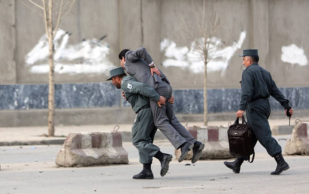 An Afghan police man carries a wounded man out of the site of a suicide attack in Kabul, Afghanistan. The suicide car bombing in the heart of the Afghan capital killed several people and wounded tens, according to Afghan security officials.