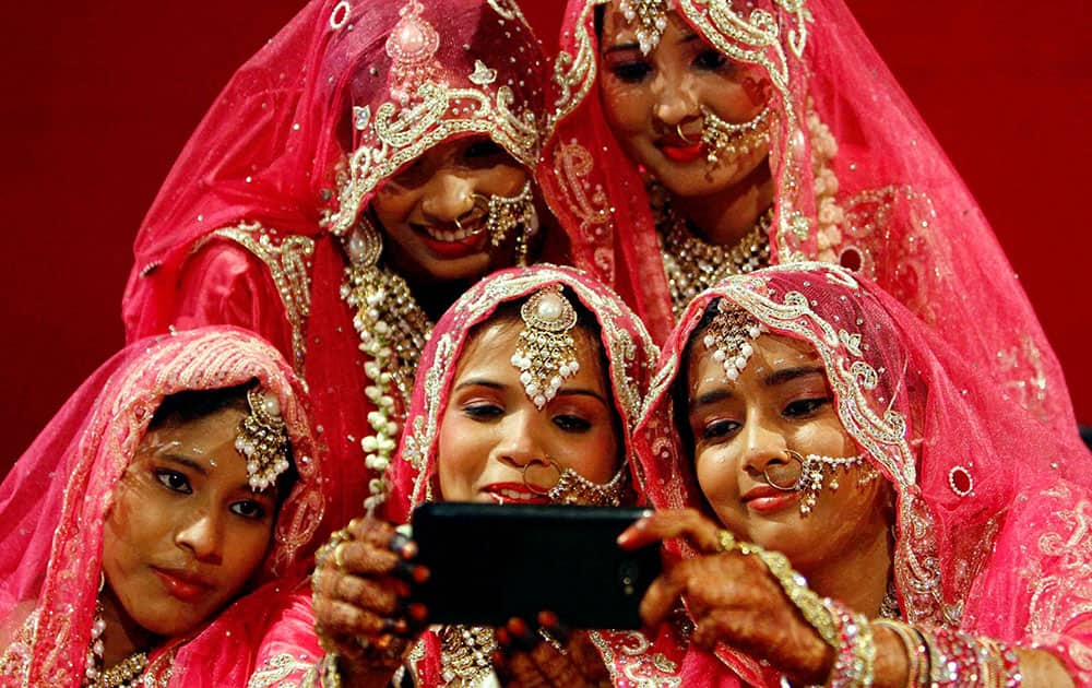 Brides dressed in traditional marriage attire take a selfie during a mass marriage ceremony in Mumbai.
