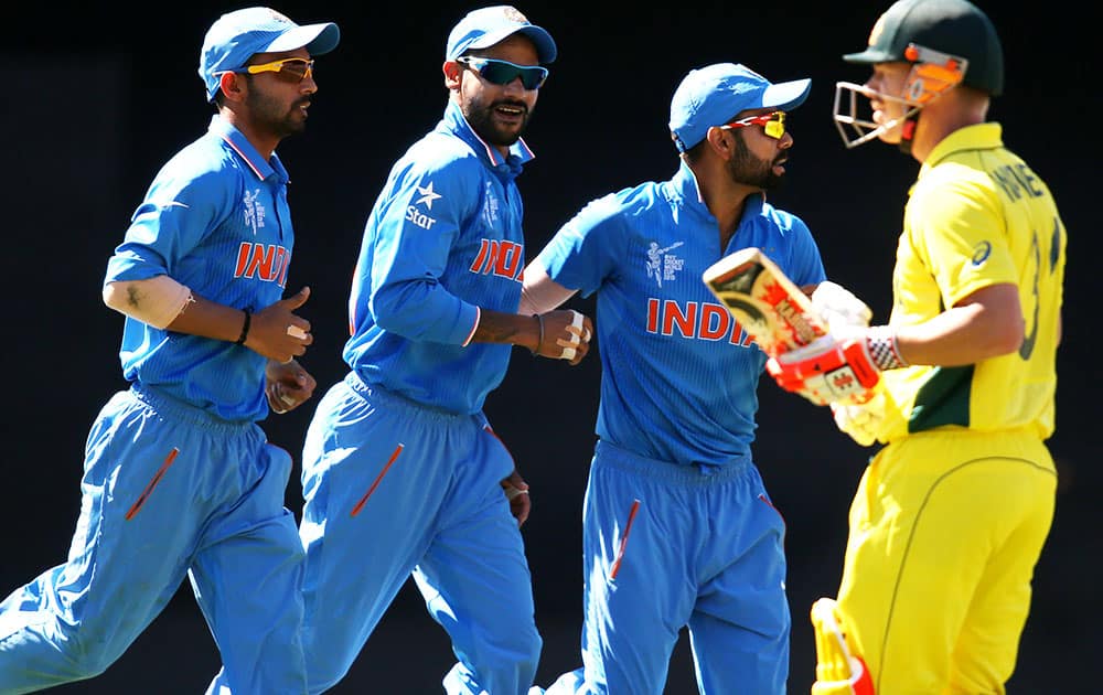 Indian players celebrate after dismissing Australian batsman David Warner, right, during their Cricket World Cup semifinal in Sydney, Australia.