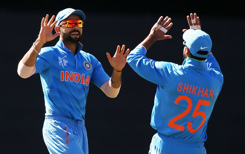 India's Virat Kohli, left, is congratulated by teammate Shikhar Dhawan after taking a catch to dismiss Australia's David Warner during their Cricket World Cup semifinal in Sydney, Australia.