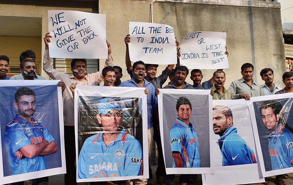 Cricket fans hold the poster of Indian Cricket players wishing them for their World Cup semi final clash against Australia to be held in Sydney, in Bengaluru.