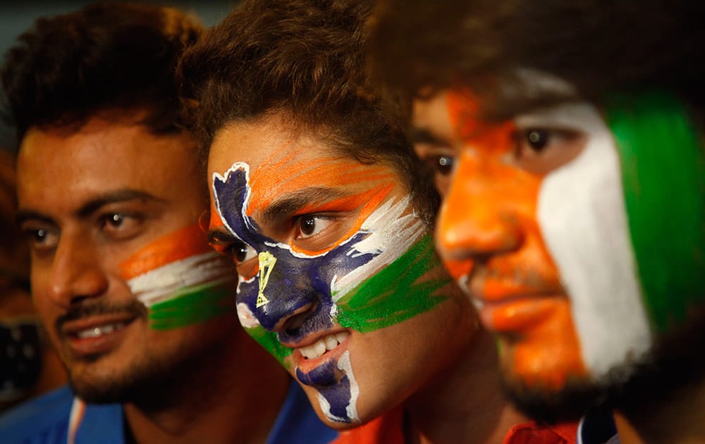 Indian cricket fans stand with their faces painted in the colors of the national flag to cheer for the Indian cricket team ahead of the ICC Cricket World Cup semifinal match against Australia, in Ahmadabad.