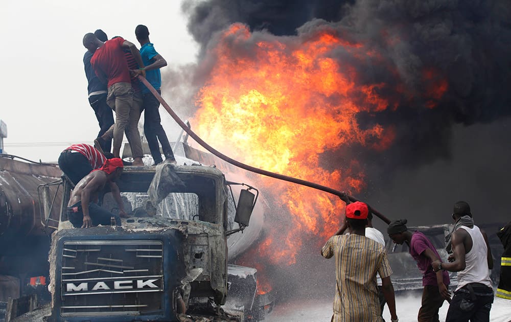 People help firefighters try to contain a fire at a petrol station in Lagos, Nigeria.