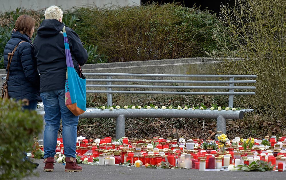 People look at flowers and candles placed in front of the Joseph-Koenig Gymnasium in Haltern, Germany.