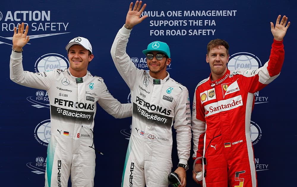 Mercedes driver Lewis Hamilton of Britain waves with teammate Nico Rosberg of Germany and Ferrari driver Sebastian Vettel of Germany after qualifying for the Malaysian Formula One Grand Prix at Sepang International Circuit in Sepang, Malaysia. Hamilton took pole position for Sunday's race ahead of Vettel. Rosberg finished third.