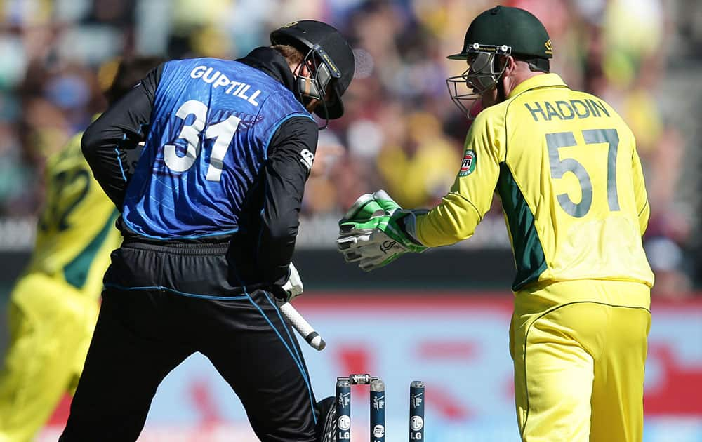 New Zealand’s Martin Guptill, left, looks down after he was bowled as Australia's wicketkeeper Brad Haddin celebrates during the Cricket World Cup final in Melbourne, Australia.