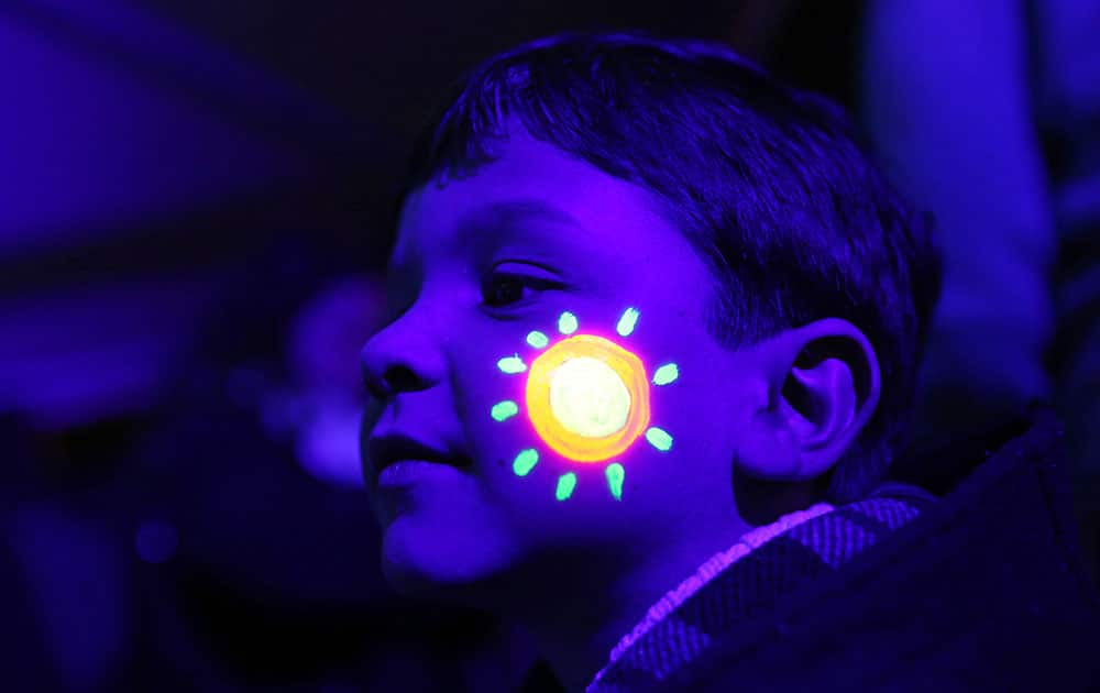 A boy with his face decorated with luminous ink poses for a photograph with others during the symbolic switching off of the lights known as Earth Hour, in Lisbon, Portugal. At 8:30 p.m. local time, individuals, businesses, cities and landmarks around the world switched off their lights for one hour to focus attention on climate change.