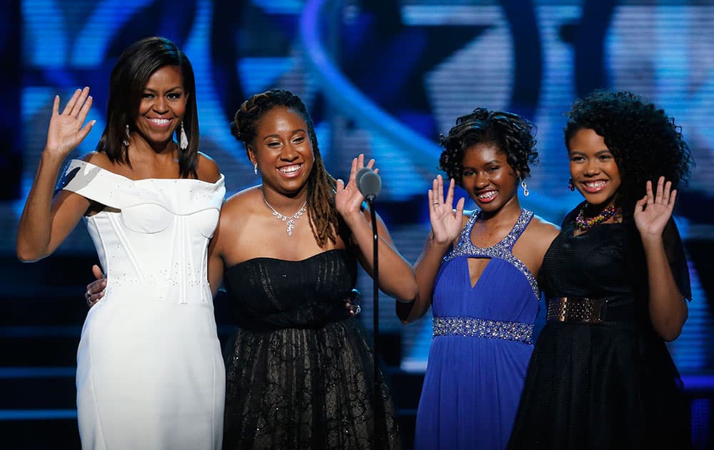 First Lady Michelle Obama, left, waves while standing on stage with Making A Difference award winners, from left, Kaya Thomas, Chental-Song Bembry and Gabrielle Jordan during a taping of the Black Girls Rock award ceremony at the New Jersey Performing Arts Center, in Newark.