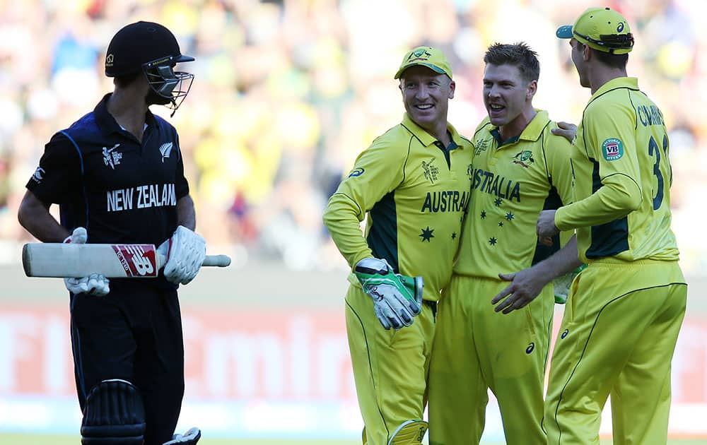 New Zealand’s Grant Elliott, left, chats with Australian players Brad Haddin, second left, and James Faulkner as Pat Cummins, right, celebrates after he was dismissed for 83 runs during the Cricket World Cup final in Melbourne, Australia.