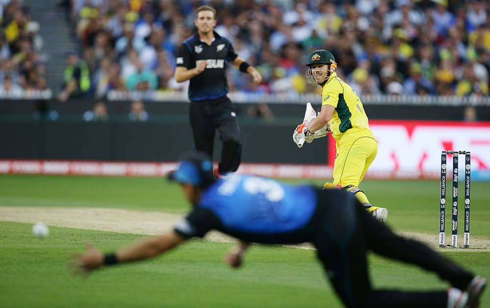 Australia's David Warner, right, watches as New Zealand’s Ross Taylor dives to field the ball during the Cricket World Cup final in Melbourne, Australia.