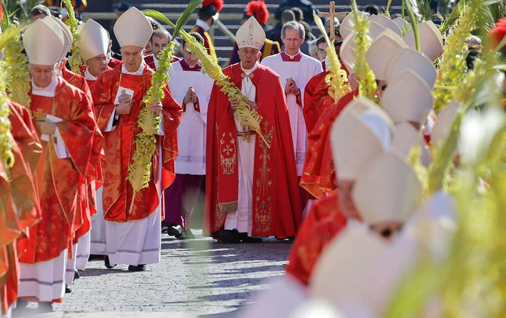 Pope Francis, center, walks in procession as he celebrates a Palm Sunday Mass in St. Peter's Square at the Vatican.