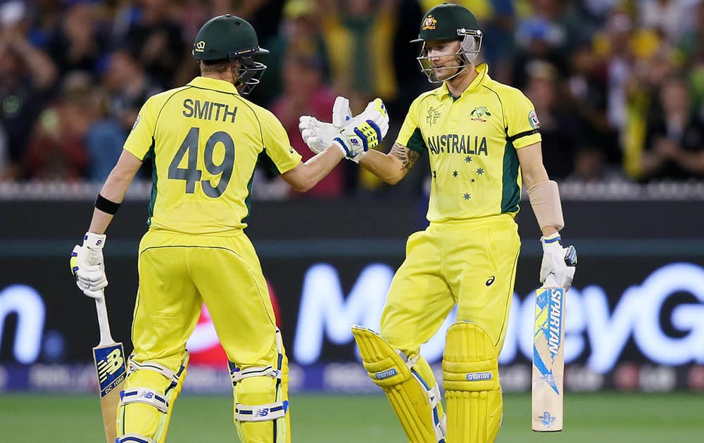 Australian captain Michael Clarke, right, is congratulated by teammate Steve Smith after scoring 50 runs while batting against New Zealand during the Cricket World Cup final in Melbourne, Australia.