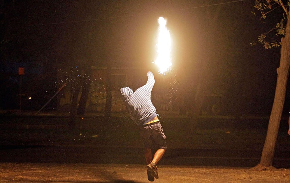 A masked man throws a petrol bomb at police during a manifestation, commemorating the 30th anniversary of the Day of the Young Fighter, that marks the deaths of two brothers who were members of an anti-government group, in Santiago, Chile.