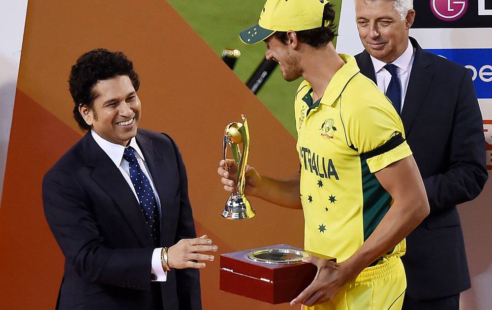 Former Indian cricketer Sachin Tendulkar, left, presents the player of the tournament trophy to Australia's Mitchell Starc at the Cricket World Cup final in Melbourne, Australia.