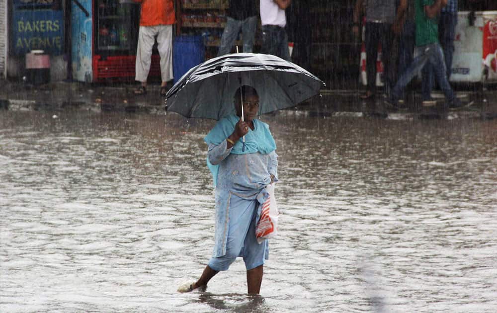 A WOMAN WADES THROUGH A WATERLOGGED STREET AFTER THE CITY RECEIVED HEAVY RAINFALL, IN JAMMU.