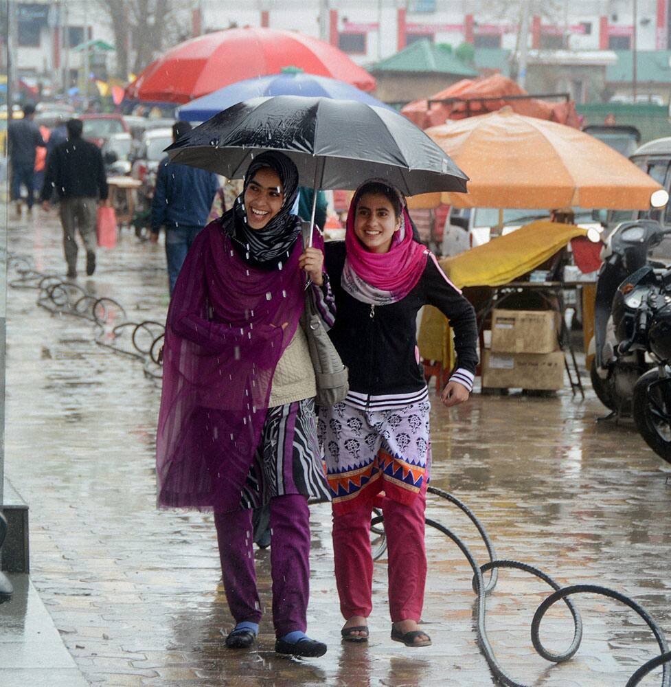 Girls walks under umberalla as it rains, at Residency Road in Srinagar.