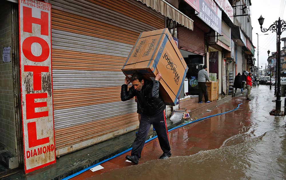A Kashmiri shopkeeper carries a washing machine on his shoulders to move it to a safer place after heavy rains flooded several areas in Srinagar.