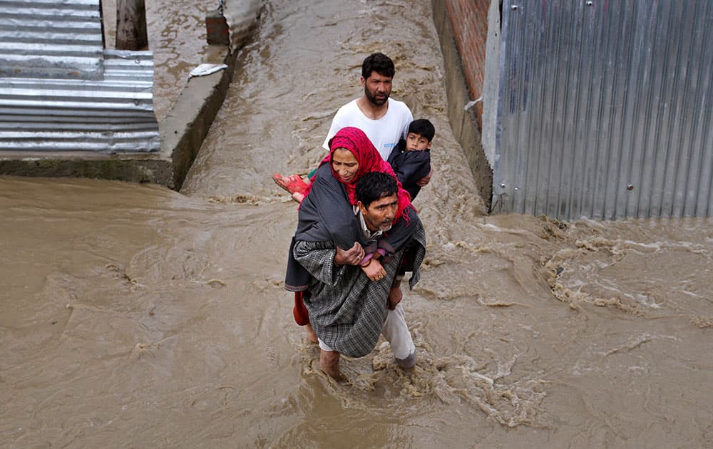 Kashmiri men assist a woman and a child to evacuate from a flooded area in Srinagar.