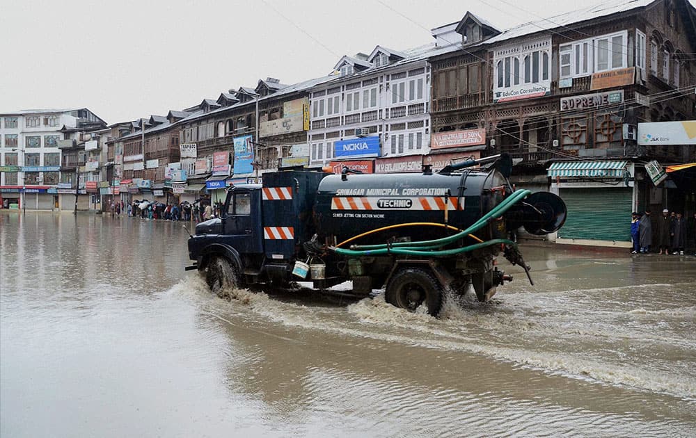 A city municipal corporation van passes through a waterlogged road after the valley received heavy rainfall, in Srinagar.