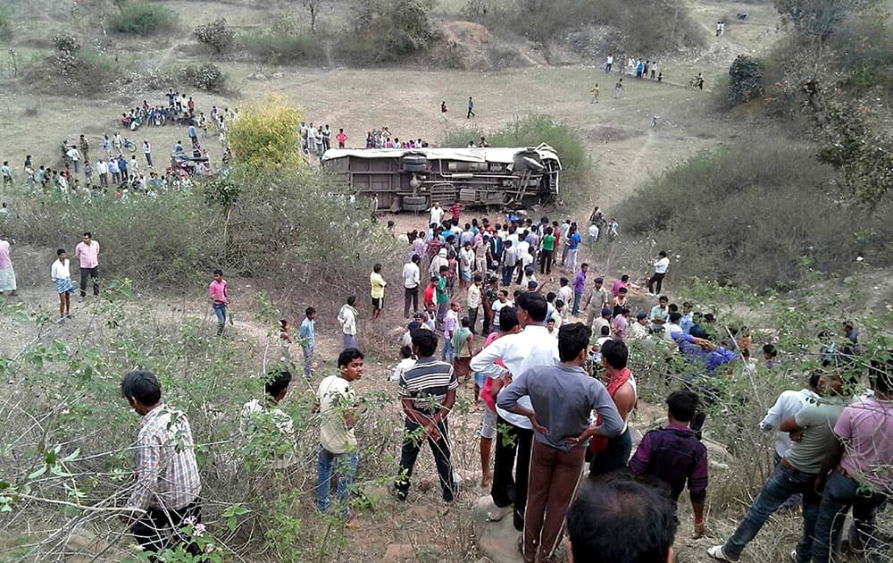 People gather near a passenger bus that overturned after it plunged into a gorge, in Garhwa district of Jharkhand state, India.