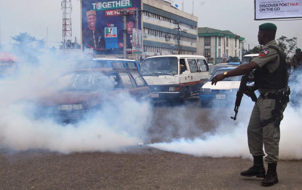 A Nigerian soldier stands next to a tear gas canister as it sprays gas into traffic during a protest by members of the All Progressives Congress, partyagainst voting irregularities in the presidential election in Port Harcourt , Nigeria.