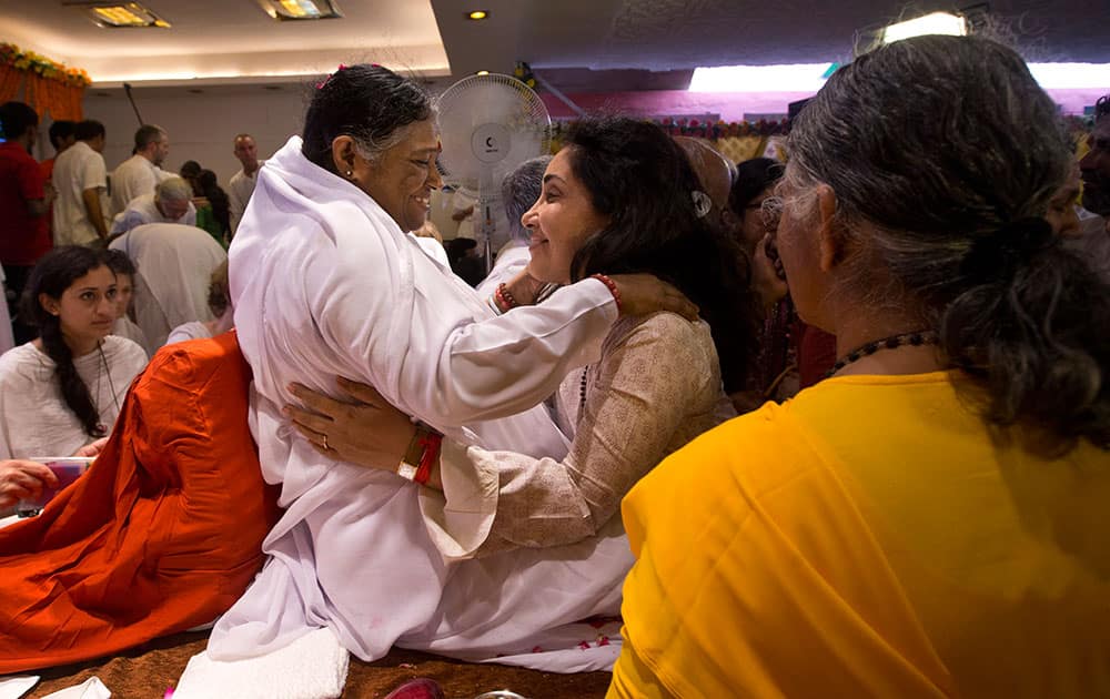 Indian spiritual leader Mata Amritanandamayi, center left, hugs to bless a devotee during a prayer meeting in New Delhi, India.